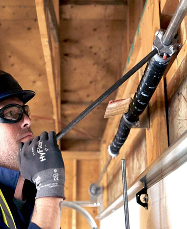  Technician performing maintenance on garage door springs in Baltimore, MD, extending the lifespan of the door mechanism.