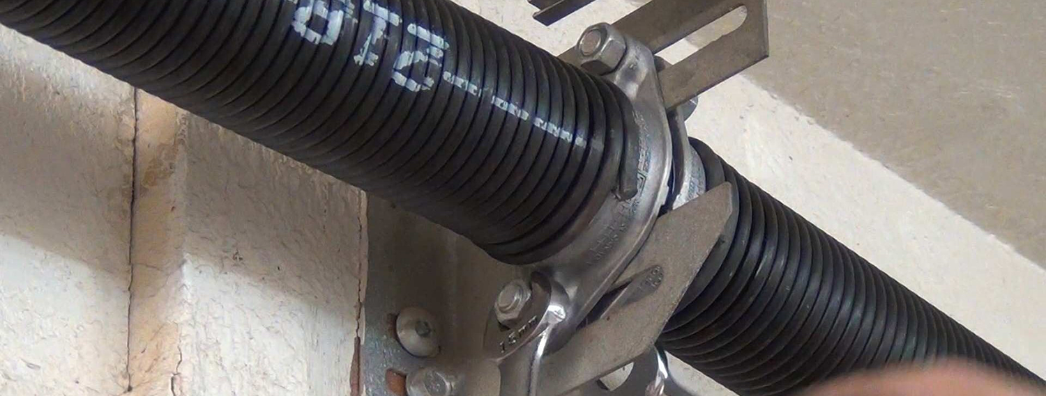 Technician repairing a torsion garage door spring in Baltimore, MD, ensuring smooth and safe door operation.
